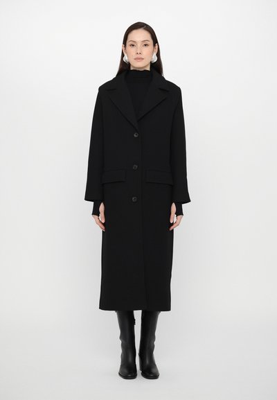 Manteau long noir avec un col cranté, design à simple boutonnage et poches latérales. Fabriqué en tissu solide avec une texture lisse.