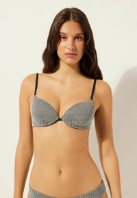 Schwarz-weiß gestreiftes Bikinioberteil mit V-Ausschnitt, Soft-Cup-Design, verstellbaren Trägern und gerafften Vorderdetails.