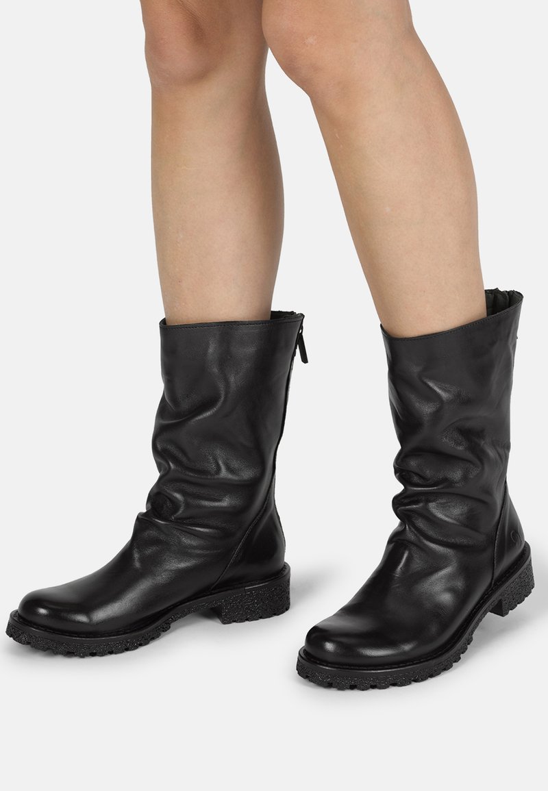 Botas de cuero negras hasta el tobillo con un diseño arrugado, superficie texturizada y una suela negra resistente con un ligero tacón y cierre de cremallera.