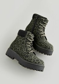 Stivaletti alla caviglia con stampa leopardata verde, dotati di un collo imbottito nero, design con lacci, zip laterale e suola spessa in gomma nera.