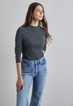 Grijze geribbelde lange mouwtop gecombineerd met lichtblauwe hoge taille spijkerbroek. De top heeft een ronde halslijn en aansluitende mouwen.