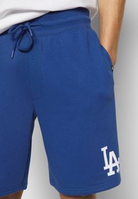 Shorts en coton bleu avec une taille élastique et un cordon de serrage. Comprend des poches latérales et un logo blanc "LA" imprimé sur la partie inférieure de la jambe.