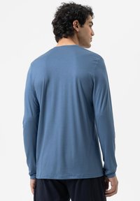 Langärmliges Hemd aus einfarbigem blauen Stoff, mit Rundhalsausschnitt und glatter Textur, entspannt geschnitten und ohne sichtbare Muster oder Akzente.