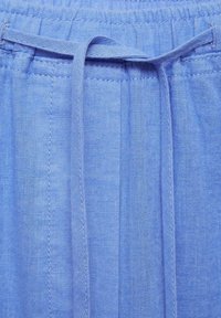 Tissu en lin bleu clair avec une taille élastique et un cordon à nouer au centre devant.