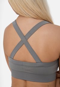 Grijze sport beha met kruislings rugontwerp, gemaakt van rekbare stof met een gladde textuur en een geribbelde onderste band.