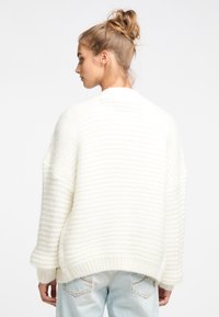 Weißer, grob gestrickter Pullover mit einem strukturierten, gerippten Design. Verfügt über überschnittene Schultern und einen lockeren Schnitt, der unter der Taille endet.