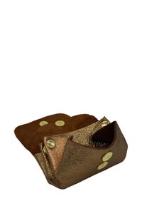 Petit plateau ouvert en cuir marron avec des boutons-pression dorés aux coins, utilisé pour contenir de petits objets.