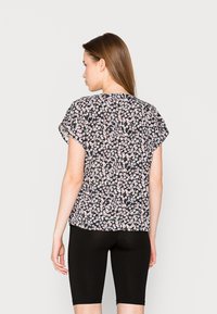 T-shirt floral com fundo preto, flores brancas e rosas, mangas curtas e um corte descontraído. Combinado com calções pretos.