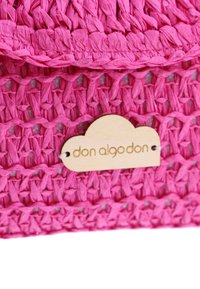 Bolso tejido en color rosa, fabricado con un material texturizado, que presenta una etiqueta de madera con el nombre grabado "don algodon" en forma de nube.