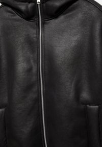 Svart hoodie i konstläder med hel dragkedja, två sidofickor, en slät yta och en kroppsnära passform.