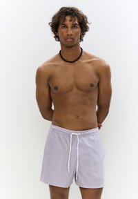 Csíkos fürdőnadrág fehér és lila színben, rugalmas derekú, zsinóros megoldással, könnyű anyagból készült, oldalsó zsebekkel.