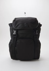 Musta reppu mattapintaisena, taitettavalla läpällä ja etutaskulla, jossa on vetoketju. Varustettu säädettävillä remmeillä ja metallisilla yksityiskohdilla.