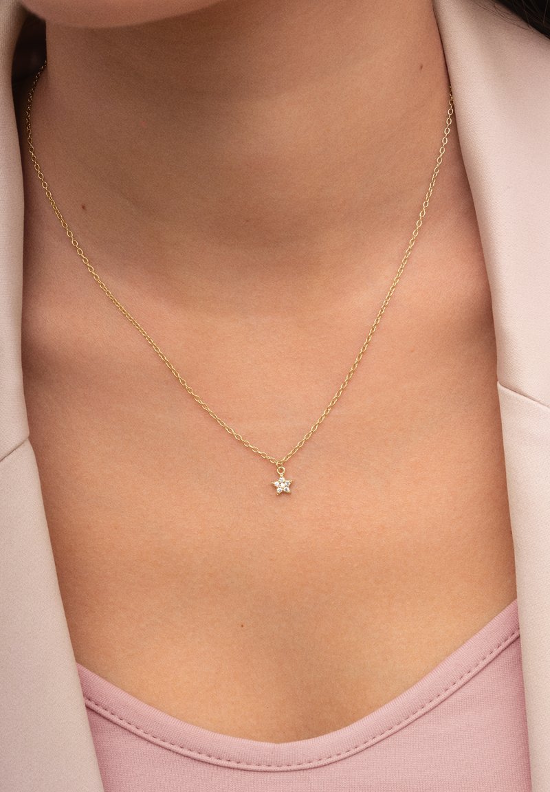 Goldene Halskette mit einem sternförmigen Anhänger und einem zentralen Edelstein. Glatte Oberfläche, feine Gliederkette und elegantes Design.