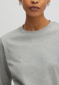 Grijze katoenen sweatshirt met een klassieke ronde hals en ribbelafwerking bij de kraag; zachte textuur en casual pasvorm.