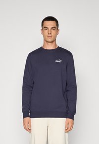Navy blue sweatshirt in a solid color, crew neck design, soft texture, featuring a white Puma logo on the left chest. Long sleeves.