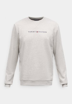 Világosszürke pulóver, puha anyagból készült, kerek nyakkivágással és hosszú ujjakkal. A pólón a "TOMMY HILFIGER" logó látható sötétkék színben, piros kiegészítéssel.