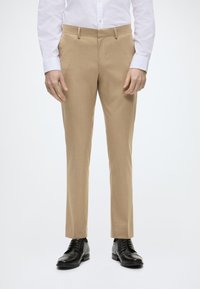 Pantaloni bej, croiți, dintr-un material fin, texturat. Față plată, bucle pentru curea și o croială slim, asortați cu pantofi de dress negri.