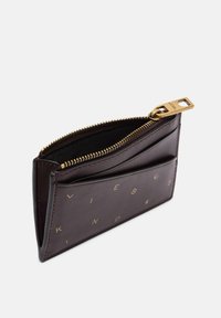 Skórzany portfel w ciemnym burgundzie, z elementami w złotym odcieniu, zamknięciem na zamek błyskawiczny oraz wytłoczonymi literami na przedniej stronie. Kompaktowy i elegancki design.