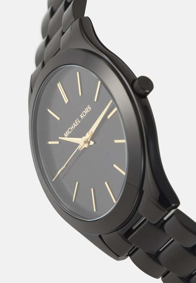 Reloj de pulsera negro Michael Kors con marcadores y manecillas doradas, con una correa de metal enlazada y esfera redonda que muestra la hora 2:11:39.