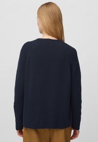 Granatowy sweter dzianinowy z teksturowanym wzorem, rękawami raglanowymi oraz ściągaczem przy dekolcie, o luźnym kroju i średniej długości.