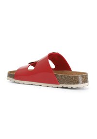 Sandalo in pelle verniciata rossa con due sezioni intagliate, soletta in sughero e suola texture. Il cinturino alla caviglia include una fibbia decorativa.
