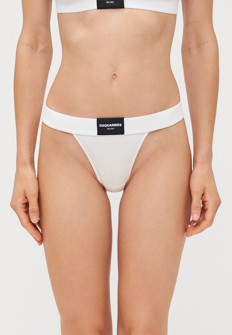 White thong underwear featuring a thick waistband with a black label displaying "DSQUARED2 MILANO." Made from a soft, stretchy material.