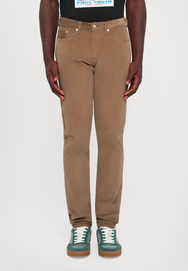 Brune kordfløjpants med slim fit, der har fem lommer, sølvhardware og bæres med grønne ruskinds sneakers.