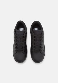 Czarne trampki z gładką skórzaną cholewką, akcentami z siateczki, okrągłym noskiem i płaskimi sznurowadłami. Zaprojektowane z niskoprofilową sylwetką.