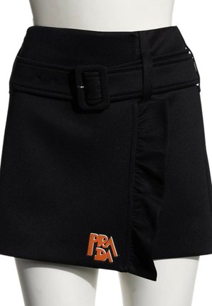 Sort kort nederdel med bælte, flæsedetalje foran og orange Prada-logo nær kanten på venstre side.