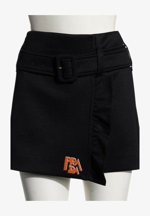 Jupe courte noire avec ceinture, détail à volants sur le devant, et logo Prada orange près de l'ourlet du côté gauche.