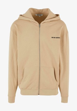 Dzsörzé színű cipzáras kapucnis pulóver, puha pamut keverékből készült, kenguru zsebbel, bordázott mandzsettákkal és diszkrét logóval a mellkasán.