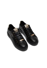 Juodos odinės sneaker'iai, turintys tekstūruotą paviršių, auksinius akcentus ant liežuvėlio ir akių, bei guminius padais su žemu profiliu.