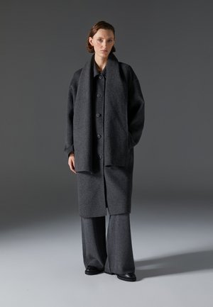 Gray wool coat with large buttons, paired with wide-leg gray trousers. Soft texture and oversized fit enhance the minimalist design.