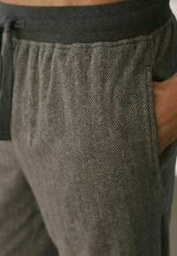Grau-Hosen mit Fischgrätmuster, dunkelgrauem elastischem Bund und Seitentaschen. Weicher Stoff, der sich gut für legere Kleidung eignet.