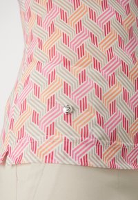 Mønstret bluse med zigzag-design i rosa, orange og beige. Har en sølvfarget knapp nær kanten. Lett stoffkvalitet.