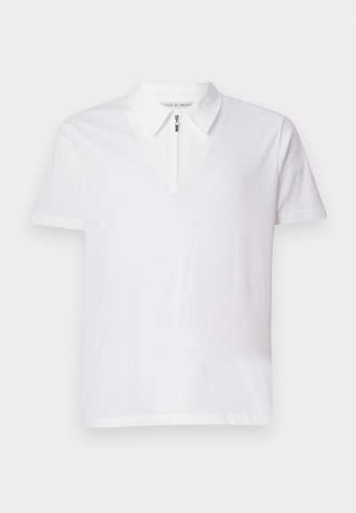 Camisa polo branca de manga curta com colarinho com fecho, feita de tecido de algodão suave, apresentando um brilho sutil e linhas limpas.