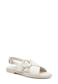Sandal in pelle bianca con punta aperta e design incrociato. Presenta una fibbia metallica circolare e un tacco in legno basso. Cinturino regolabile sul retro.