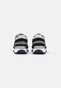Zwarte en grijze sportschoenen met gaasstof, suède accenten en een witte zool. Bevat "Saucony" branding op de hiel.