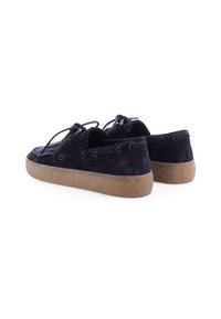 Marineblauwe enzymed schoenen met een gestructureerde rubberen zool, voorzien van drie gaten, veters en een laag profiel ontwerp. Achteraanzicht.