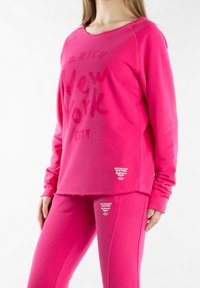 Felpa rosa con scritta "New York City", scollo rotondo, maniche lunghe e pantaloni rosa abbinati con dettaglio del logo all'orlo.