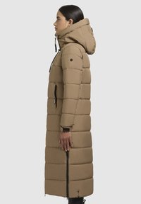 Lang, gewatteerde winterjas in beige, met een capuchon, verticale stiknaaddesign, ritszakken aan de zijkant en een volledige rits aan de voorkant.