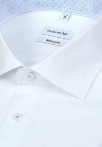 Chemise blanche à col avec boutons et étiquettes indiquant la marque Seidensticker, taille 15 ½ M 39 et coupe régulière.