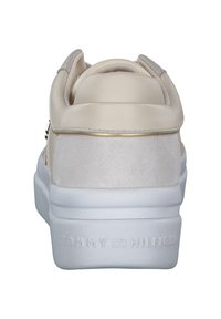 Beżowe sneakersy z gładkiej skóry i zamszu, biała podeszwa, złoty akcent na pięcie oraz wytłoczone logo marki z tyłu.