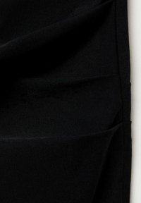 Černá látka s hladkým texturem, s řasením a záhyby. Materiál se zdá být měkký a elastický, s konzistentní tmavou barvou.