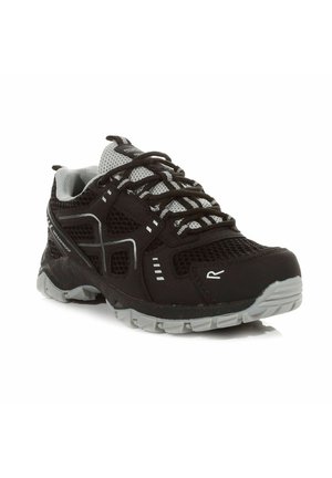 Chaussure de sport imperméable noire et grise avec des panneaux en mesh, des détails réfléchissants et une semelle grise solide, inclinée pour montrer l’avant et le côté.