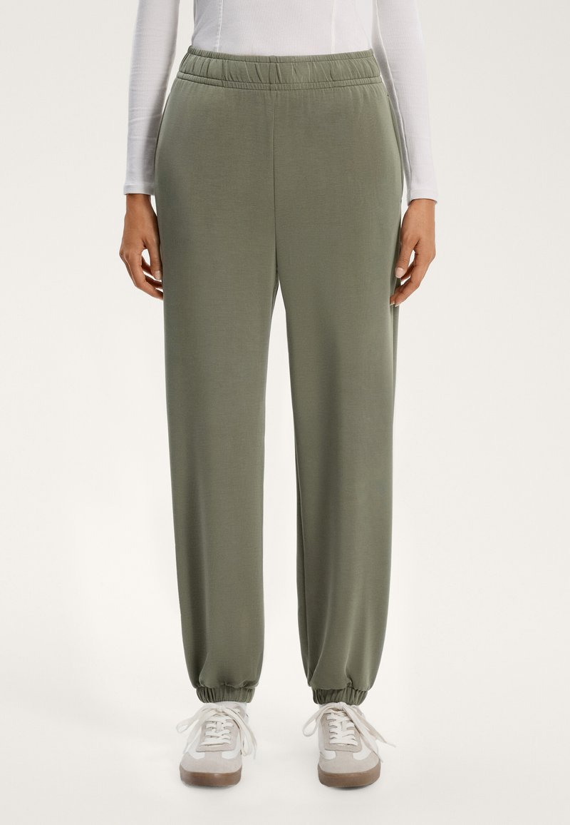Kalhoty se zvýšeným pasem v olivově zelené barvě z měkké tkaniny; elastické manžety na kotnících, boční kapsy, volný střih s pohodlným pasem.