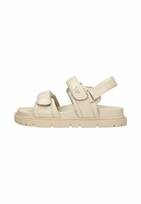 Sandali beige con cinturini in Velcro regolabili, suola spessa e testurizzata, punta arrotondata e logo discreto sul cinturino.