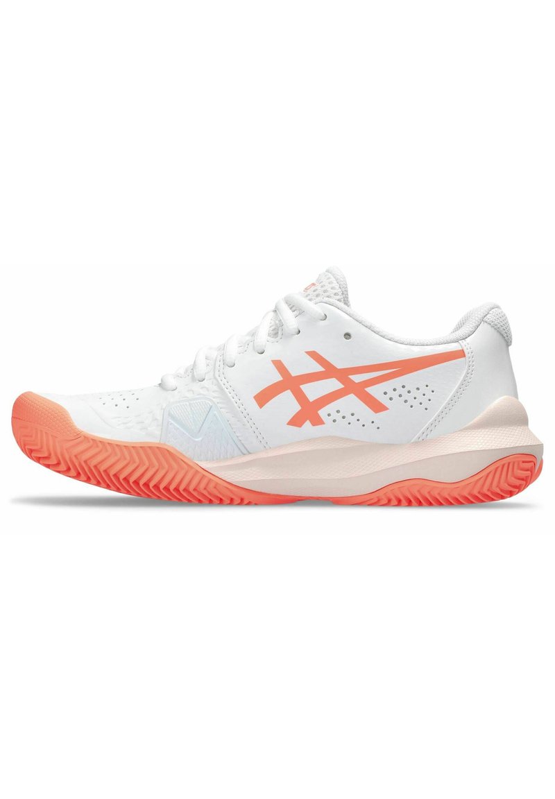 Zapatilla deportiva blanca con acentos naranjas, que presenta un upper texturizado, cierre con cordones y una suela de goma con patrón para mayor agarre.