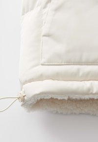 Dikke crèmekleurige buitenkleding met een zachte, gestructureerde fleece voering en een verstelbare koord aan de onderkant. Inclusief een patch pocket aan de voorkant.