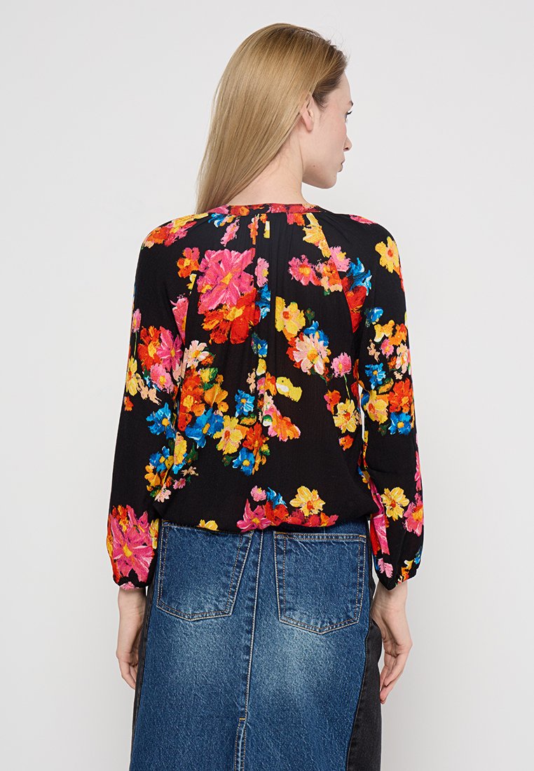 Kwiatowa bluzka z długimi rękawami, zdobiona jaskrawymi różowymi, pomarańczowymi i niebieskimi kwiatami na czarnym tle. Projekt obejmuje marszczoną linię dekoltu.